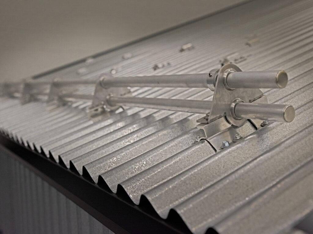 Sistema de retención de nieve DualGard instalado en un techo metálico corrugado.