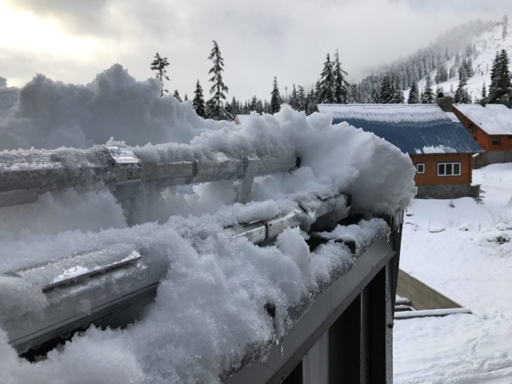 Sistema de retención de nieve instalado en el borde de un techo metálico cubierto de nieve.