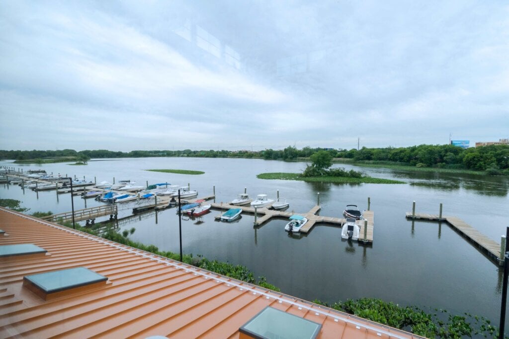 Un gran edificio de una marina con un distintivo tejado naranja y múltiples ventanas, situado junto al agua con barcos atracados en las cercanías.