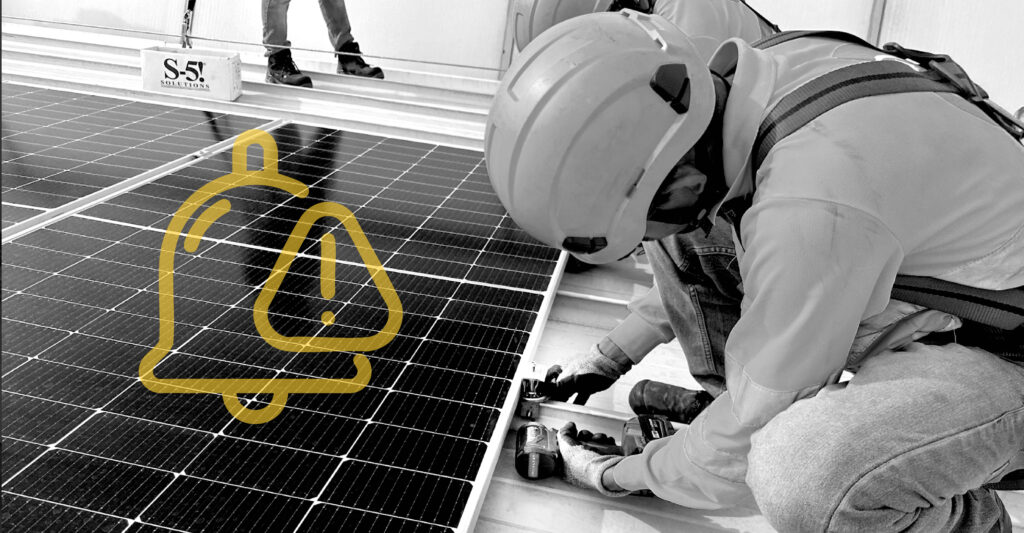 Un instalador solar montando paneles solares en un techo de metal.