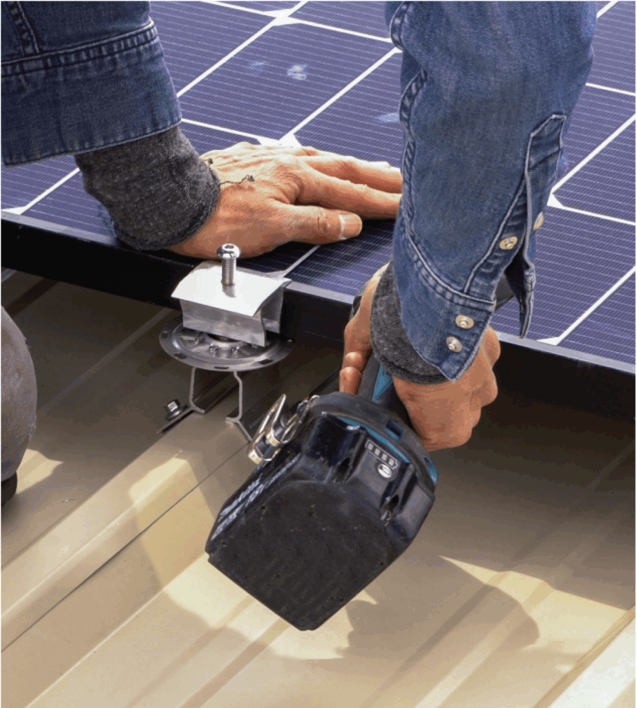 Un hombre asegura un panel solar usando una pistola de tornillos para instalar PVKIT con RibBracket I-V.