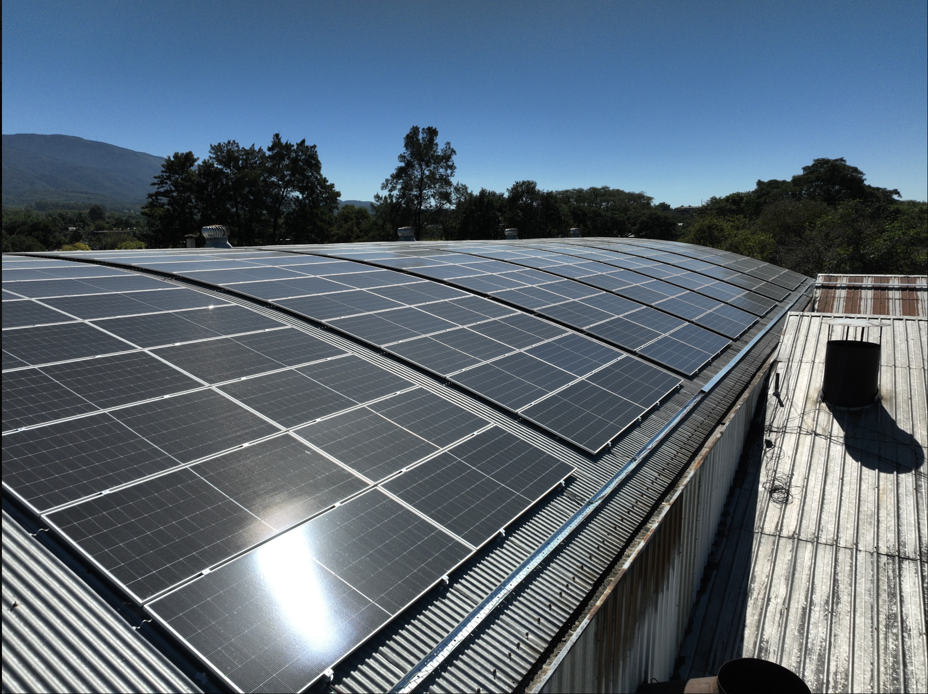 Aerial view of a distribution warehouse featuring a large rooftop solar array, highlighting commercial solar energy, industrial photovoltaic systems, renewable power generation, and sustainable logistics infrastructure.